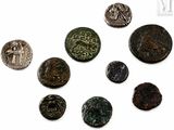 Plusieurs pièces de monnaie romaines antiques sont disposées en cercle sur une surface blanche.