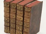 three old books are stacked on top of each other on a white surface