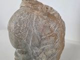 a stone sculpture of a woman ' s head on a white surface