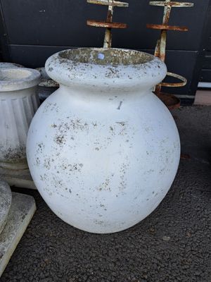 deux vases blancs posés par terre à côté d'une poubelle