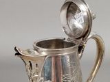 a silver pitcher with a lid on a table