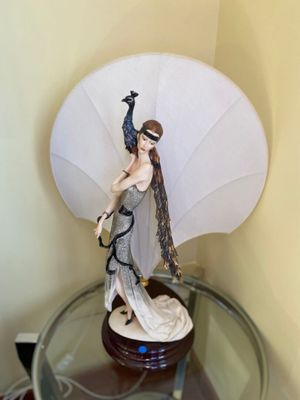 a figurine of a woman with a peacock on top of a glass table