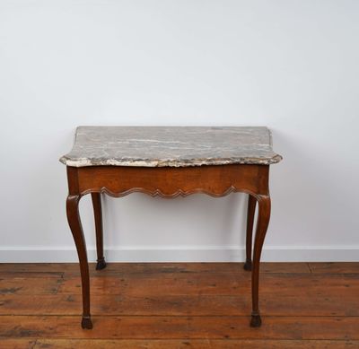 une vieille table en bois avec un plateau en marbre, posée sur un parquet en bois massif