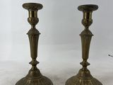 une paire de bougeoirs anciens en laiton posés sur une table en marbre