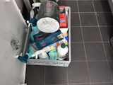 a basket full of cleaning supplies on the floor of a bathroom