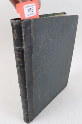 un vieux livre noir orné d'une étiquette rouge, tenu par une main