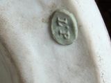 a close up of a white vase with a green seal on it