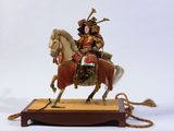 une figurine représentant un homme à cheval, posée sur un socle en bois