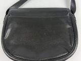 a black leather purse with a strap hanging from it ' s shoulder