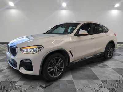 un SUV BMW blanc garé dans un garage au sol carrelé