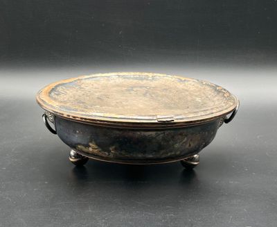 an old metal bowl sitting on top of a black table