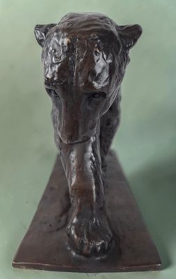 bronze statue of a tiger on a wooden base on a green background