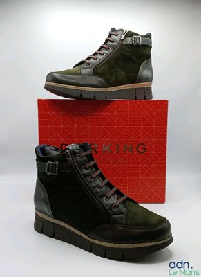 des chaussures pour homme dans une boîte rouge, accompagnées d'une paire de bottes vertes