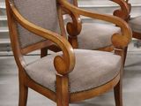 two wooden chairs with beige upholstered cushions in a room