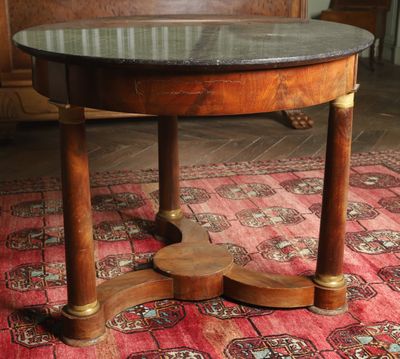 une table ronde avec un plateau en marbre posée sur un tapis rouge
