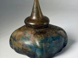 a blue and brown vase sitting on a white surface
