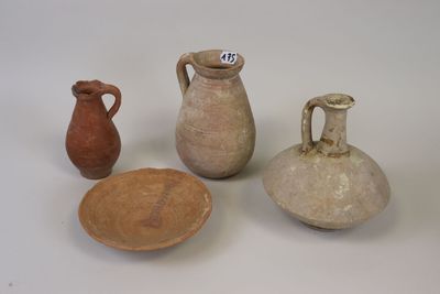 three clay vases and a plate on a white surface