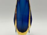 a blue and yellow vase sitting on a white surface