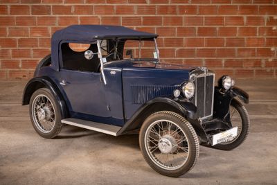 a vintage car parked in front of a brick wall