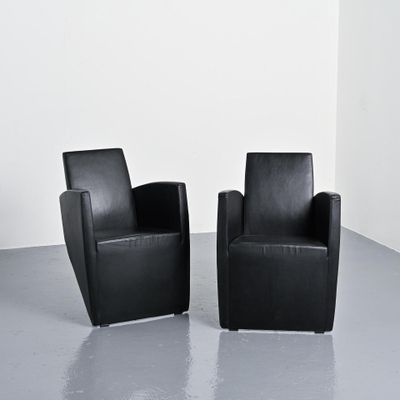 pair of black leather chairs in a white room with a white wall