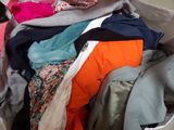 a bag full of clothes and a cat sitting on the floor