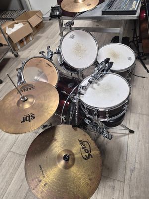 a drum set that is sitting on the floor in front of a laptop