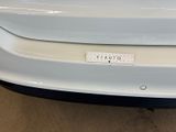 the rear end of a white car with a sticker on it