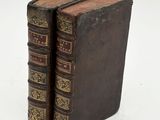 two old books sitting on top of each other on a white surface