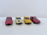 quatre petites voitures sont alignées sur une surface blanche