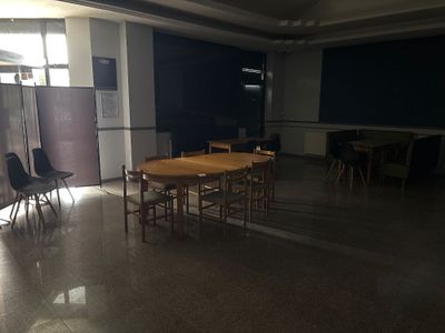 des tables et des chaises dans une pièce, avec un tableau noir en arrière-plan