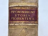 Une personne tient dans sa main un vieux livre sur lequel sont inscrits des mots