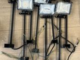 six projecteurs posés sur un plancher en bois, auxquels sont rattachés de nombreux fils électriques