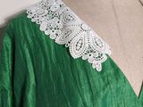 a green dress with a white lace collar on a mannequin