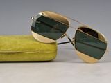 pair of gold sunglasses with green lenses sitting on a yellow case