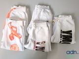 three pairs of white pants with orange ties on them sitting on a table