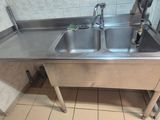 un évier en acier inoxydable dans le coin d'une toilette publique