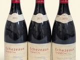 trois bouteilles de vin rouge posées l'une à côté de l'autre sur une surface blanche