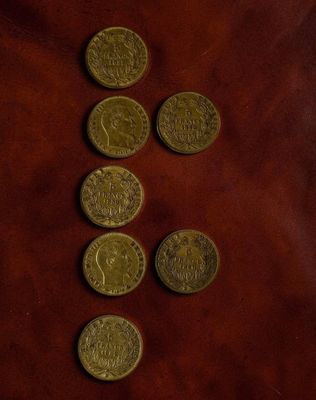 a bunch of coins sitting on top of a brown leather surface