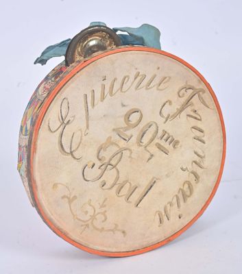 un petit tambour portant une inscription, posé sur une surface blanche