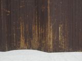 a red fire hydrant sitting in the snow next to a fence