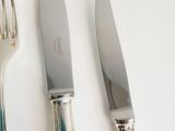 three forks and a knife on a white table