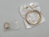 a gold bracelet and a gold ring on a white table
