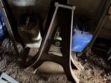 a cat that is sitting under a table in the dirt