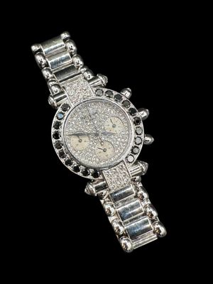 a close up of a watch on a black surface with a black background