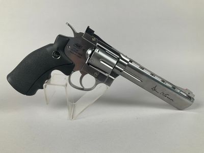 a close up of a revolver on a clear stand on a white surface