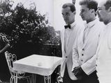 quatre hommes debout autour d'une table recouverte d'une nappe