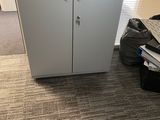 a white cabinet with a door and a black bag on the floor