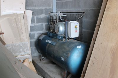 un compresseur d'air installé dans une pièce, à côté d'un tas de bois