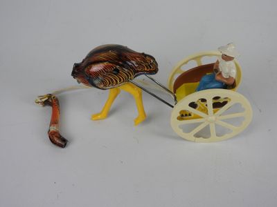 une figurine représentant une autruche tirant une charrette sur laquelle se trouve un homme
