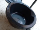 a black toilet bowl sitting on the floor next to a black trash can